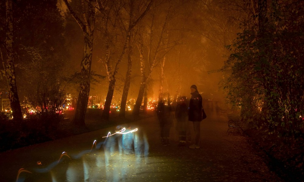 Cmentarz w nocy oświetlony zniczami