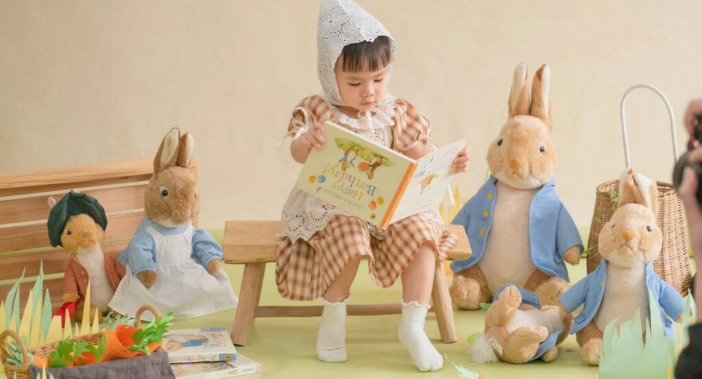 Dziecko czytające książkę w towarzystwie zabawek