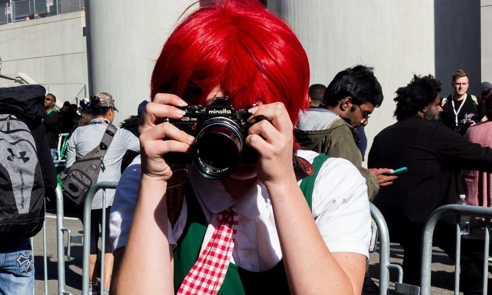 Cosplayerka z czerwonymi włosami robiąca zdjęcie fotografowi
