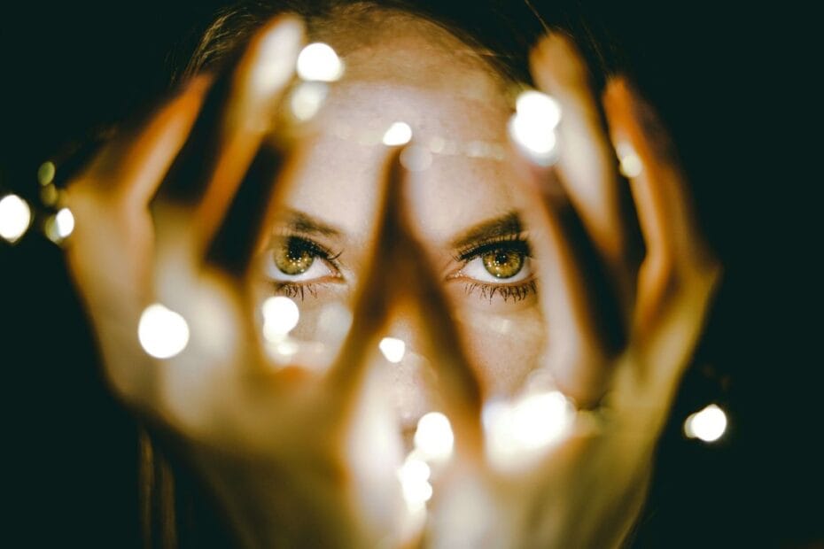 Kobieta patrząca przez dłonie i światełka