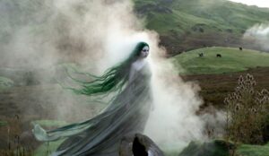 Celtycka legenda o glaistig. Blada kobieta w szarej sukni i długich zielonych włosach, otoczona mgłą. W tle zielone pastwiska